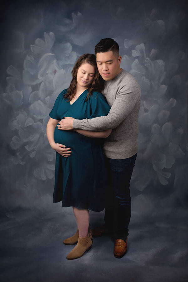 Husband and wife embracing during their studio maternity photoshoot