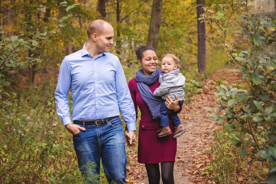 Mom and Dad walking with their baby boy down a forest path during their family photoshoot