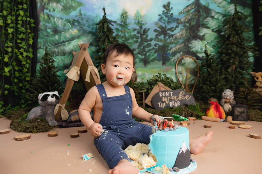 Baby boy celebrating his first birthday with a camping cake smash photoshoot