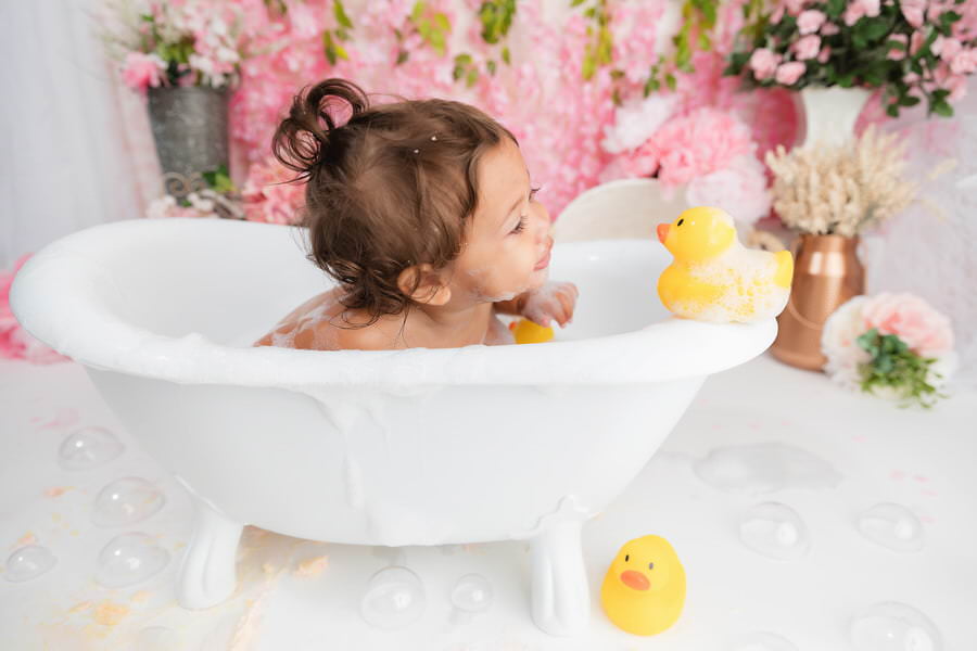 Baby girl looking at ducks during bath time at her cake smash photoshoot