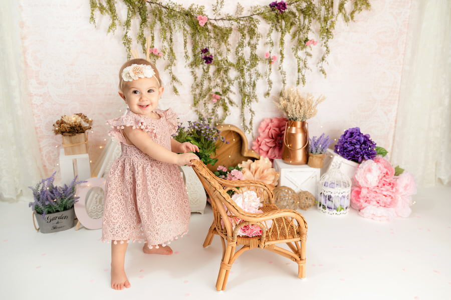 Standing baby girl at her boho themed first birthday cake smash photography session