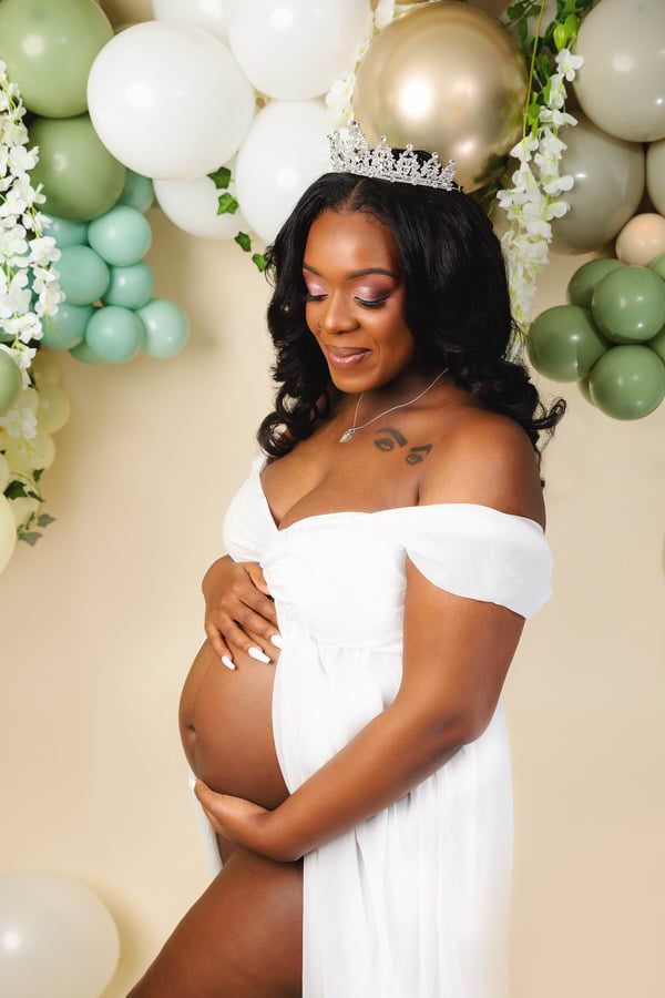 Pregnant Mom posing in a white dress during her studio maternity photoshoot