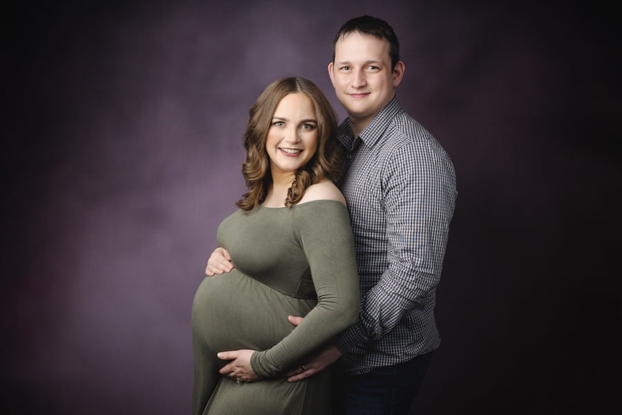 Husband and wife posing together in studio during their maternity photography session