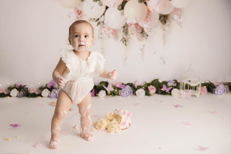 Standing baby girl at her cake smash photoshoot with floral theme