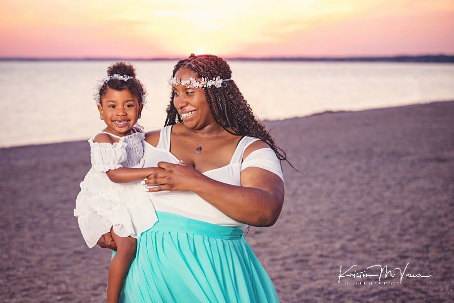 Smiling Mom and daughter snuggling during their seaside photoshoot