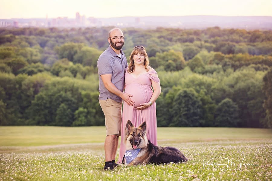 Smiling couple and their german shepard dog posing at an overlook during their family and dog maternity photos