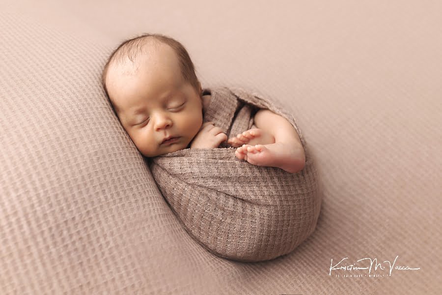 Wrapped newborn boy sleeping posing for his photoshoot on a brown blanket during his July baby newborn photos