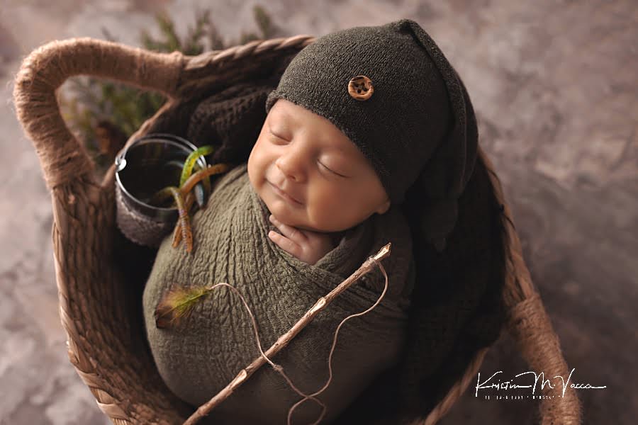Smiling and sleeping baby boy wrapped in green with fishing props posing during his photoshoot