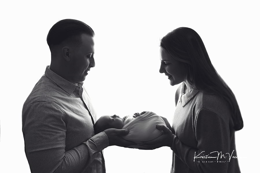 Black and white silhouetted photo of a husband and wife holding their baby.