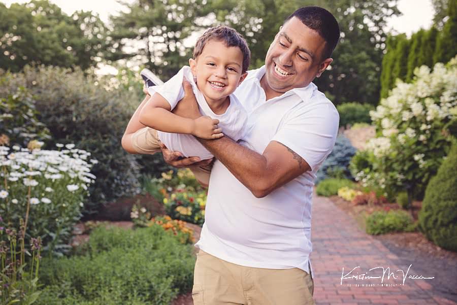 Dad swinging his laughing son around during their happy family photos by The Flash Lady Photography