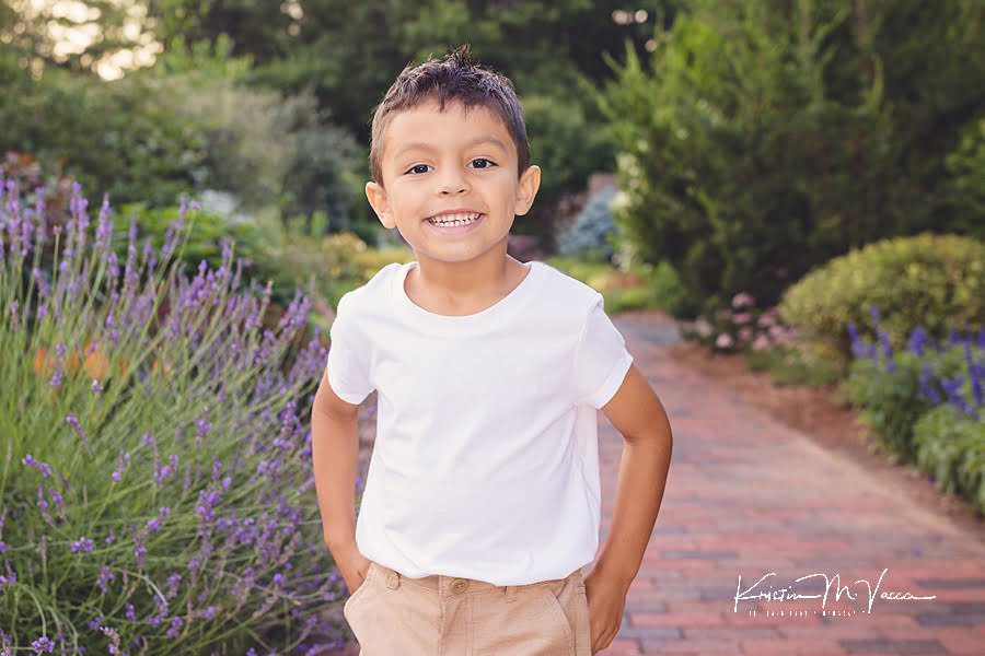 Smiling hispanic boy posing in front of lavender flowers during their photoshoot