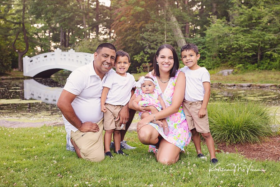 Smiling Hispanic family of 5 kneeling together for their happy family photos by The Flash Lady Photography