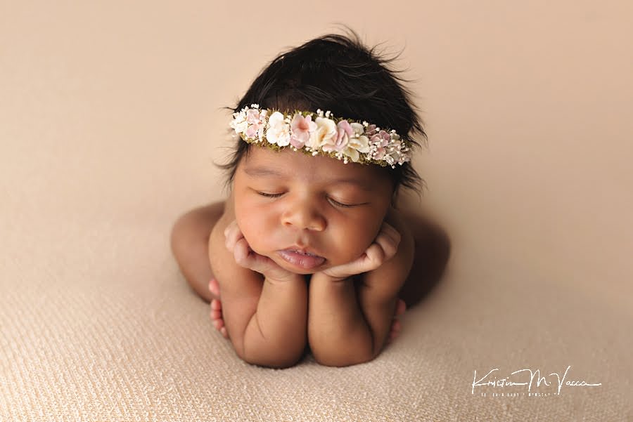 Sleeping black baby girl in a floral crown on a cream blanket with her hands under her chin by The Flash Lady