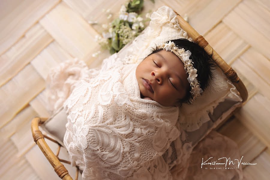 Beautiful newborn photography of a sleeping black baby girl in a bed wrapped in white lace by The Flash Lady