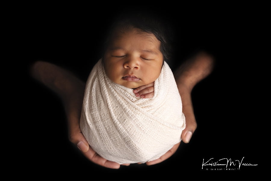 Just Dad's hands holding his sleeping black baby girl wrapped in white during her photoshoot