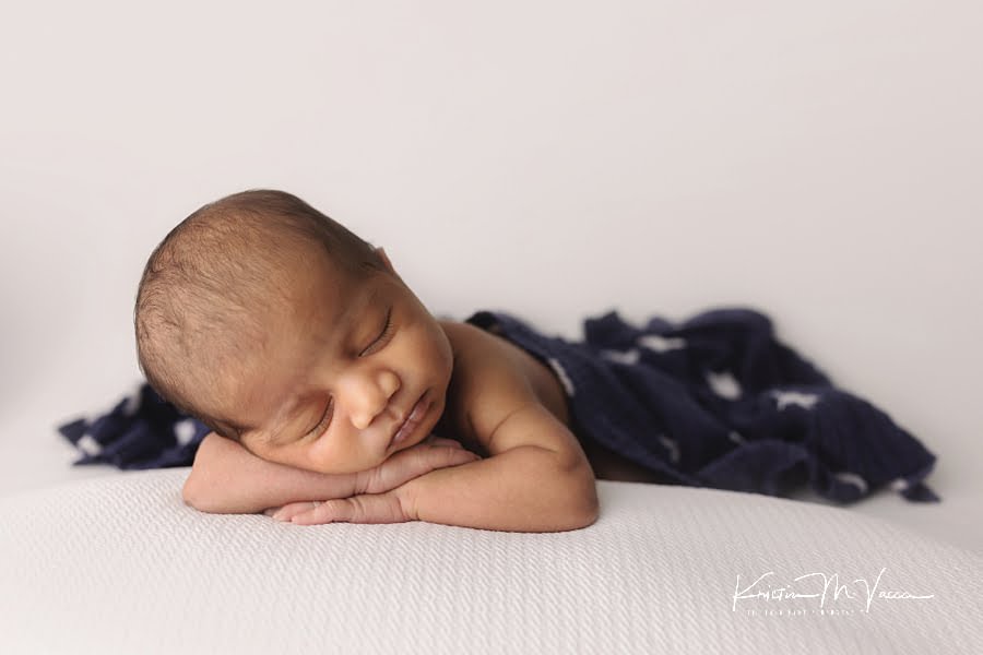 Sleeping Indian baby boy covered in a blue and white star blanket posing for his newborn photoshoot