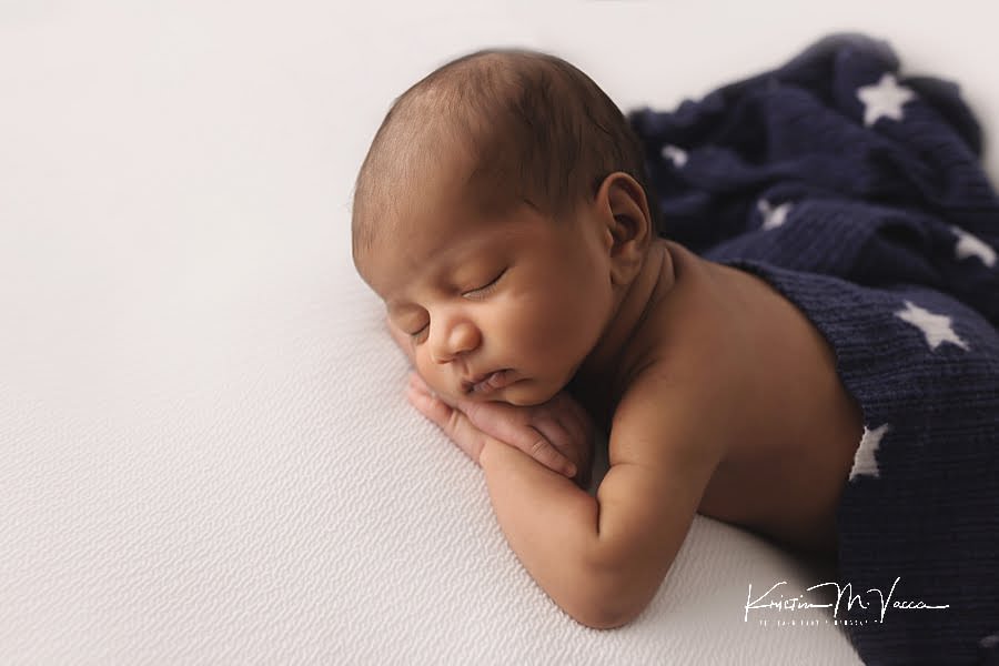 Sleeping Indian baby boy covered in a blue and white star blanket posing for his newborn photoshoot