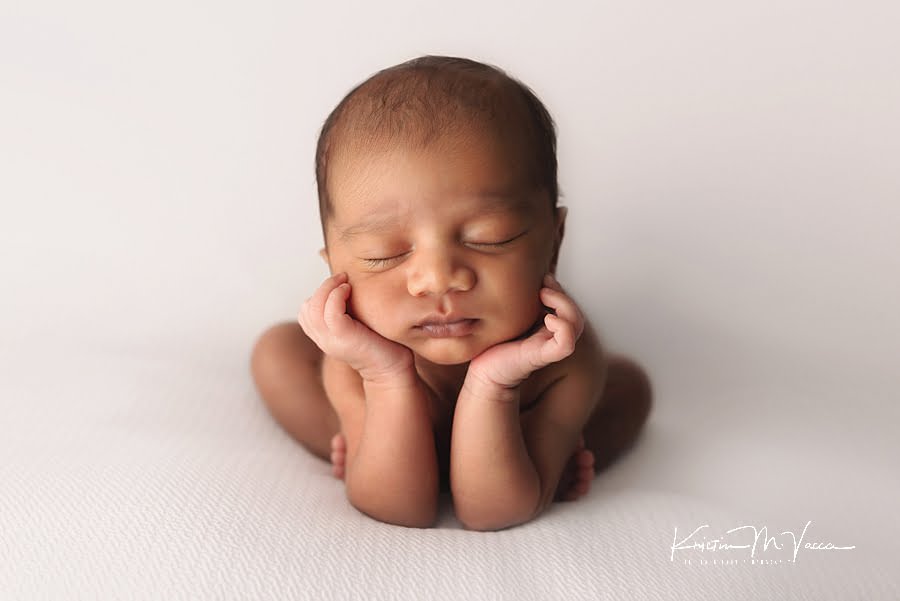 Indian infant baby boy posing with his hands under his chin for his newborn photos with older brother