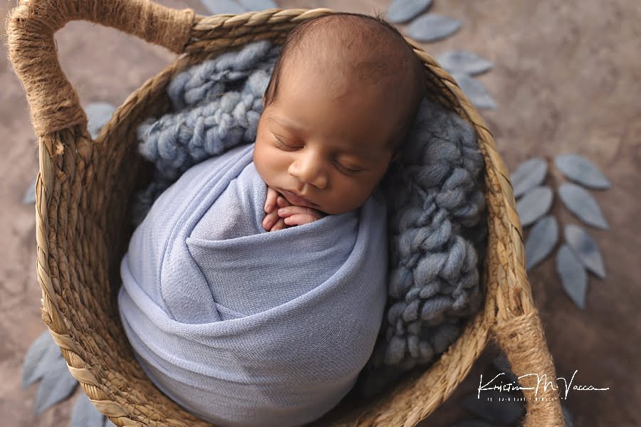Indian infant boy sleeping wrapped in blue posing for his newborn photography session