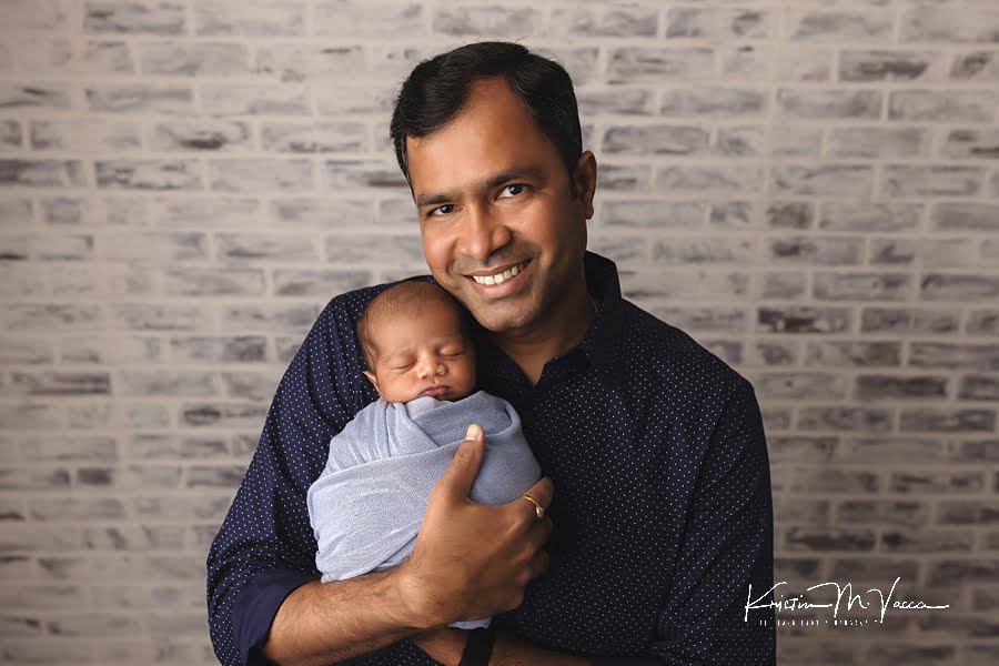 Indian father holding his sleeping newborn baby during their photoshoot