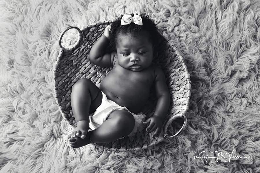 Black and white photo of a black baby girl sleeping on her back during her photoshoot