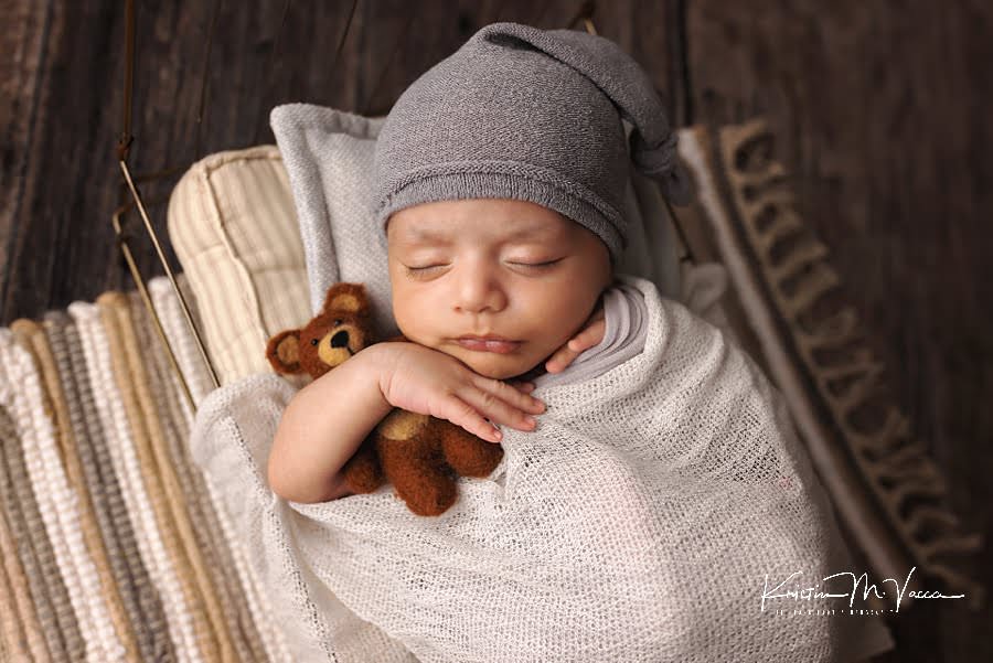 Baby boy sleeps holding a teddy bear during his 6 week old newborn photoshoot
