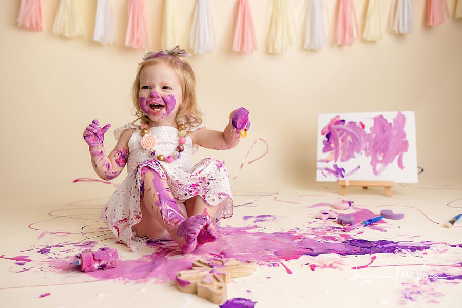 Toddler girl laughs as she's covered in paint during her photoshoot