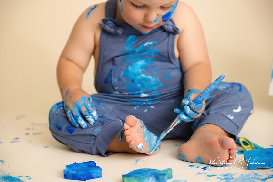 Close up of a toddler boy painting his foot during his blue paint smash