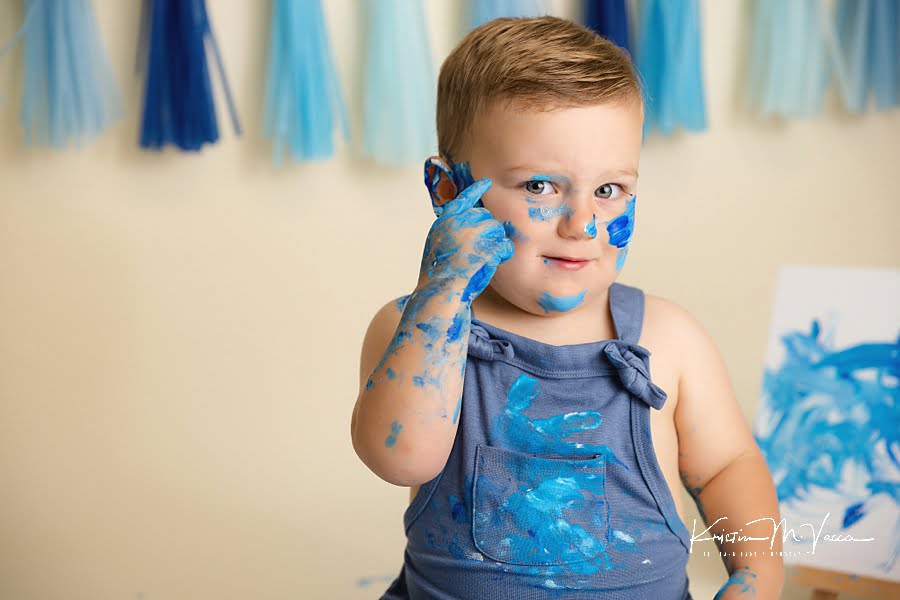 Close up of a toddler boy painting his face during his birthday photoshoot