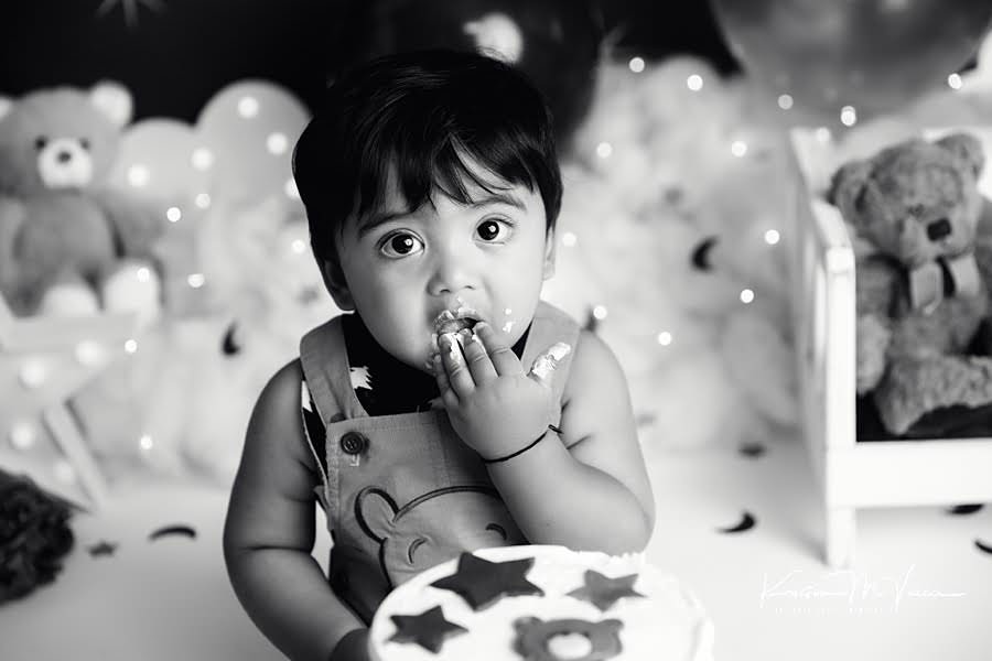 Black and white photo of a toddler boy eating cake during his birthday photoshoot