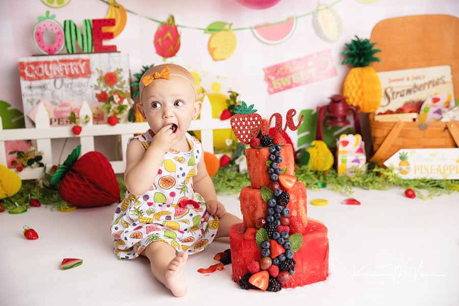 Baby girl eats a blackberry during her fruit cake smash