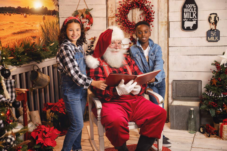 Young boy and girl read with Santa Claus during their Christmas photoshoot