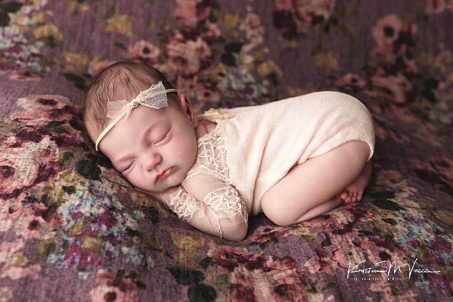 Sleeping baby girl on a purple floral blanket posing during her summer newborn photos