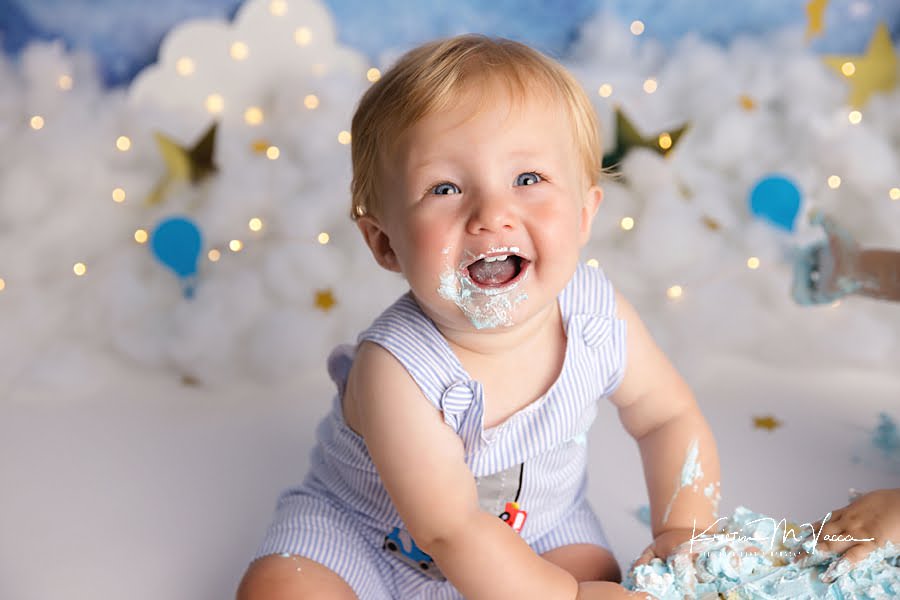 Smiling toddler boy loving his birthday cake smash