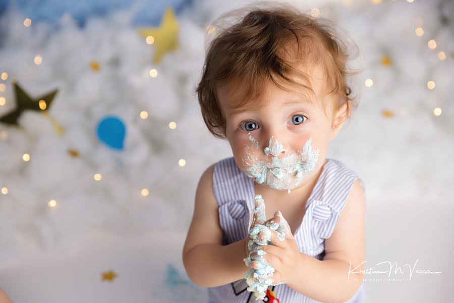 Toddler boy covered in frosting during his birthday cake smash
