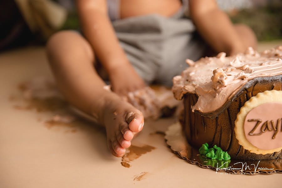 A close up of a toddler boy's foot next to his cake during his birthday photoshoot