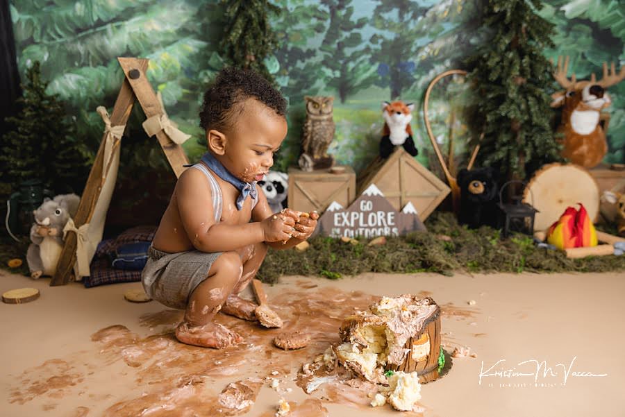 Toddler boy squats over his smashed cake during his photoshoot