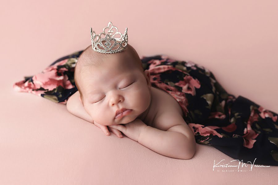 Sleeping baby girl in a crown during her pretty in pink newborn photos