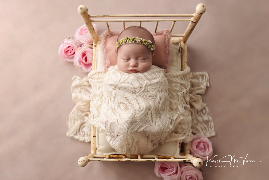 Sleeping newborn girl poses in a bed during her photoshoot
