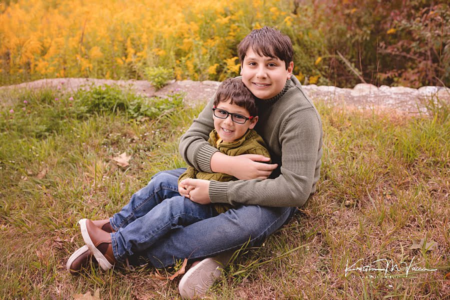 Two brothers sit together hugging during their early fall family photos