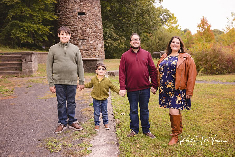 Family of 4 stands together holding hands during their fall photoshoot