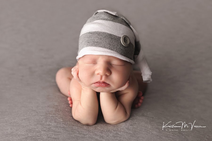 Newborn baby boy in froggie pose and a gray striped cap during his fall studio newborn photos