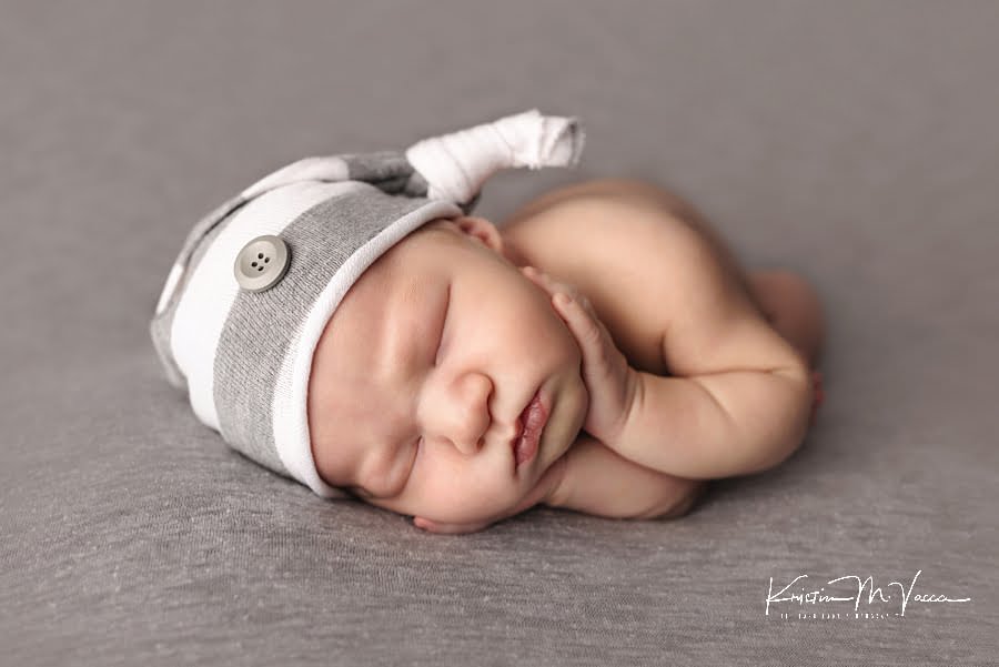 Sleeping newborn boy with his hands on his cheeks during his newborn photoshoot