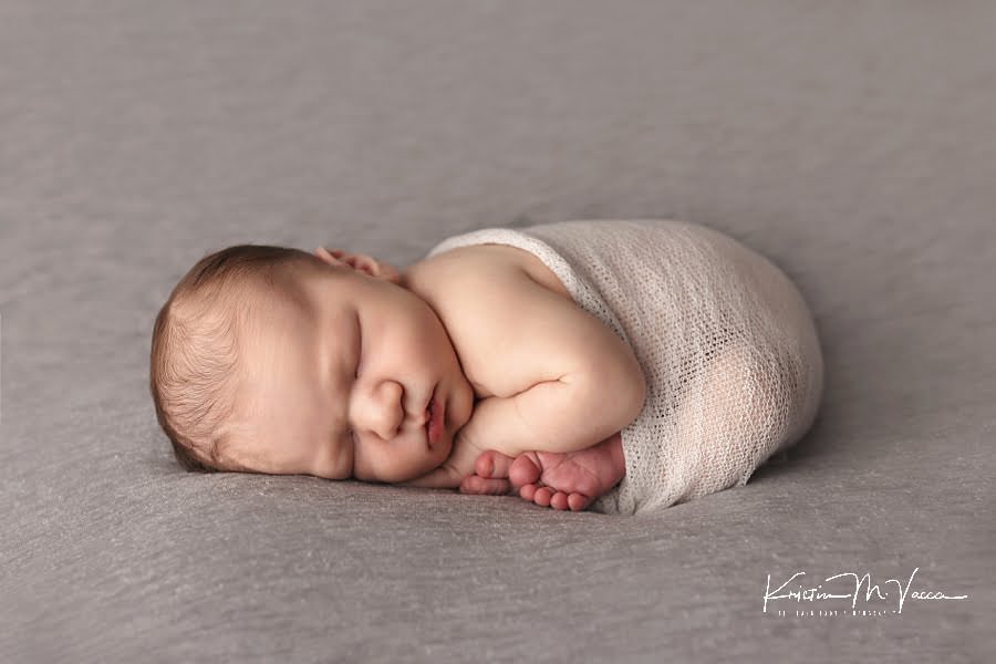 Sleeping newborn boy wrapped in gray during his fall studio newborn photos