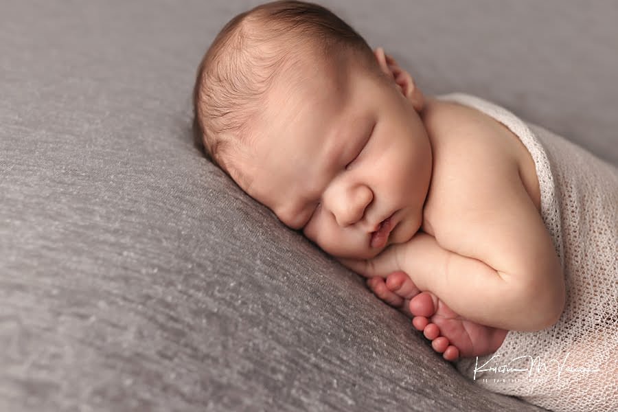 Closeup of a sleeping baby boy on a gray blanket during his photoshoot