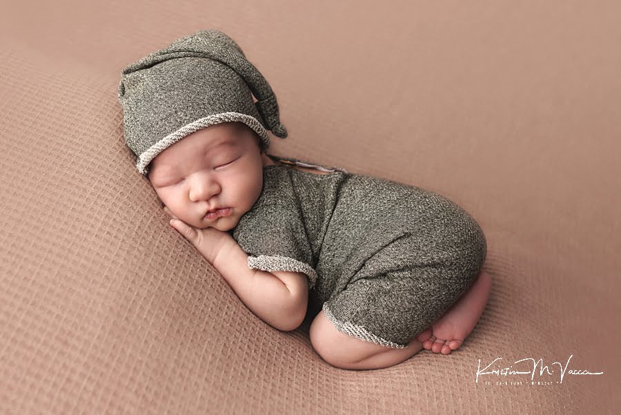 Sleeping newborn boy in a green outfit posing during his fall studio newborn photos