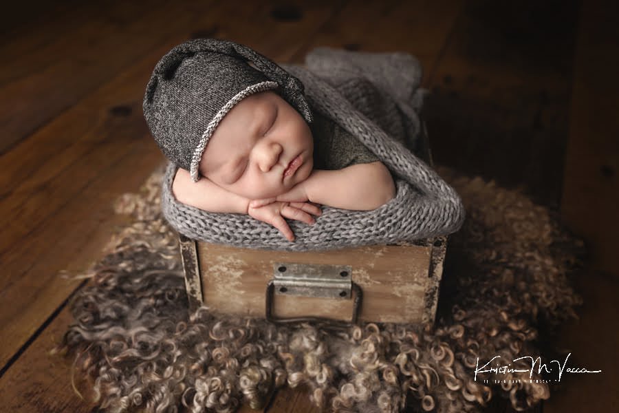 Baby boy sleeps in a drawer prop with gray hat during his fall studio newborn photos