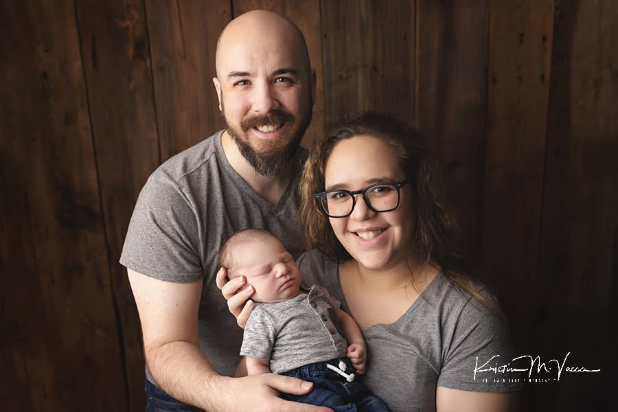 Mom and Dad smile at the camera holding their baby during their fall studio newborn photos