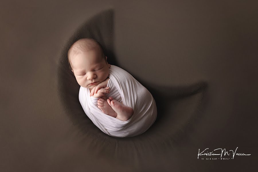 Baby boy posing in a moon prop on a green blanket during his fall studio newborn photos
