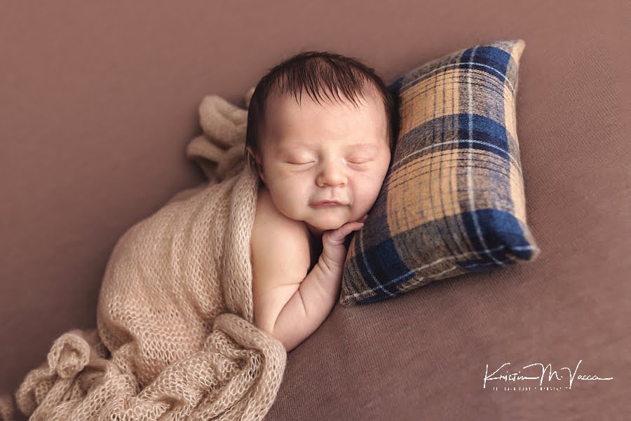 Sleeping baby boy lies on a striped pillow during his fall woodland newborn photos
